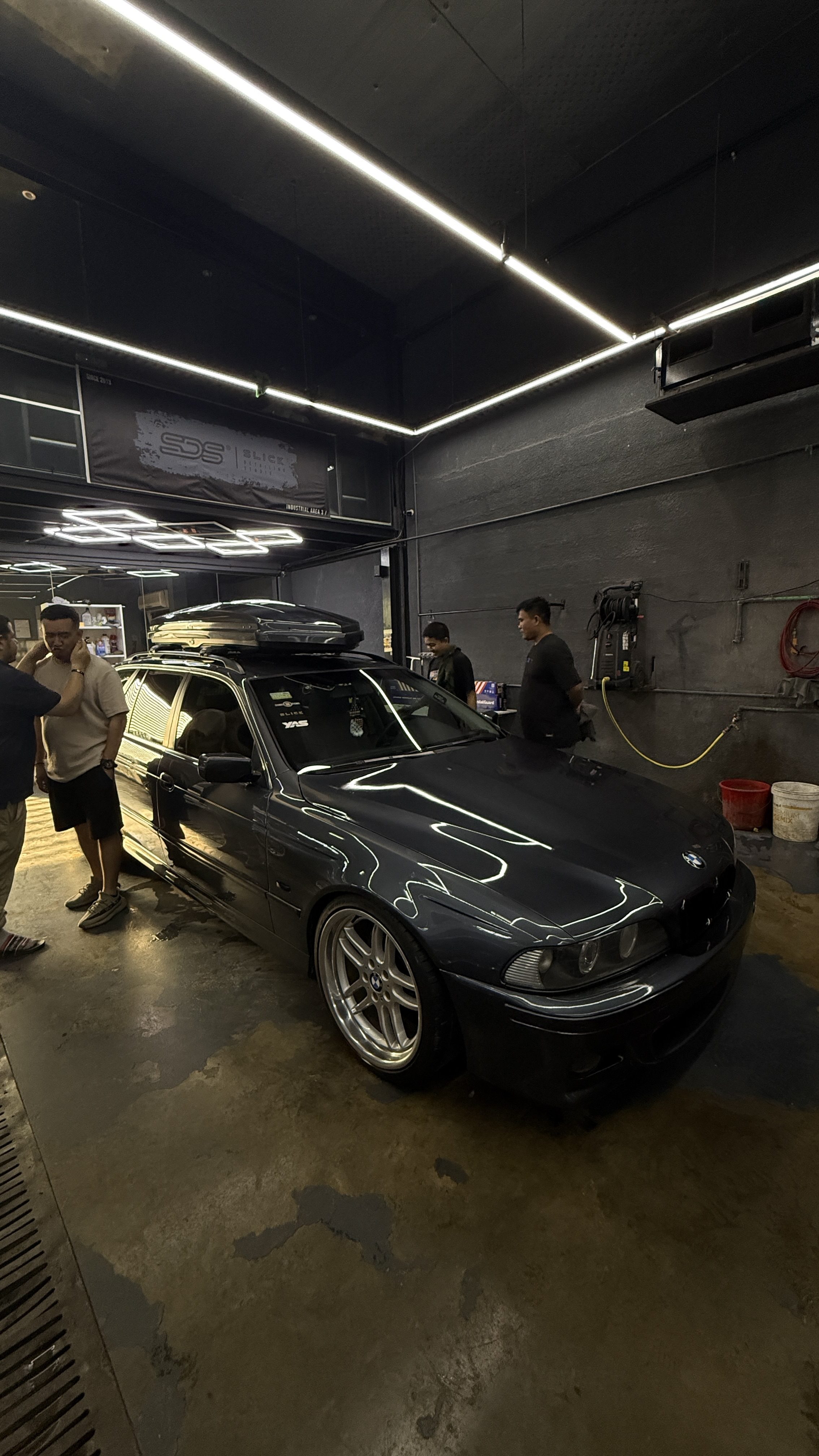 A dark BMW 5 Series on the workshop floor