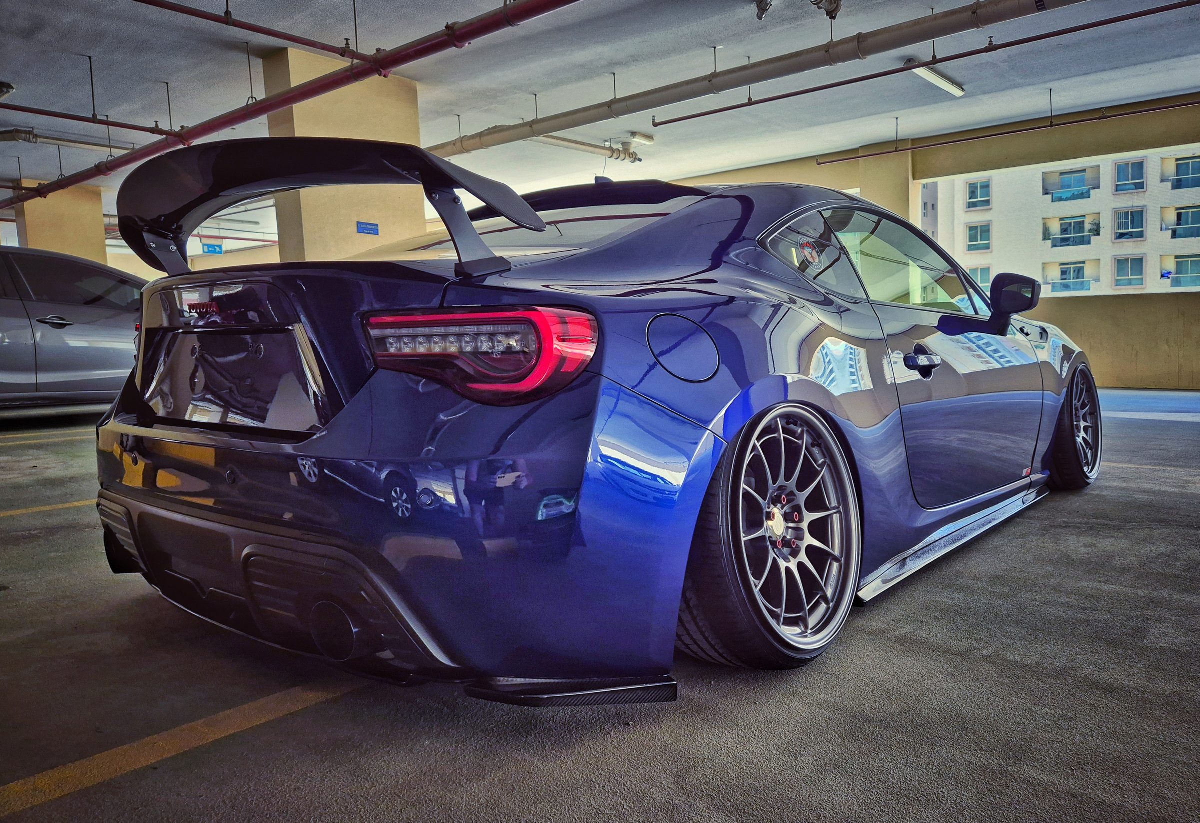 A widebody custom build with a rear wing photographed from behind