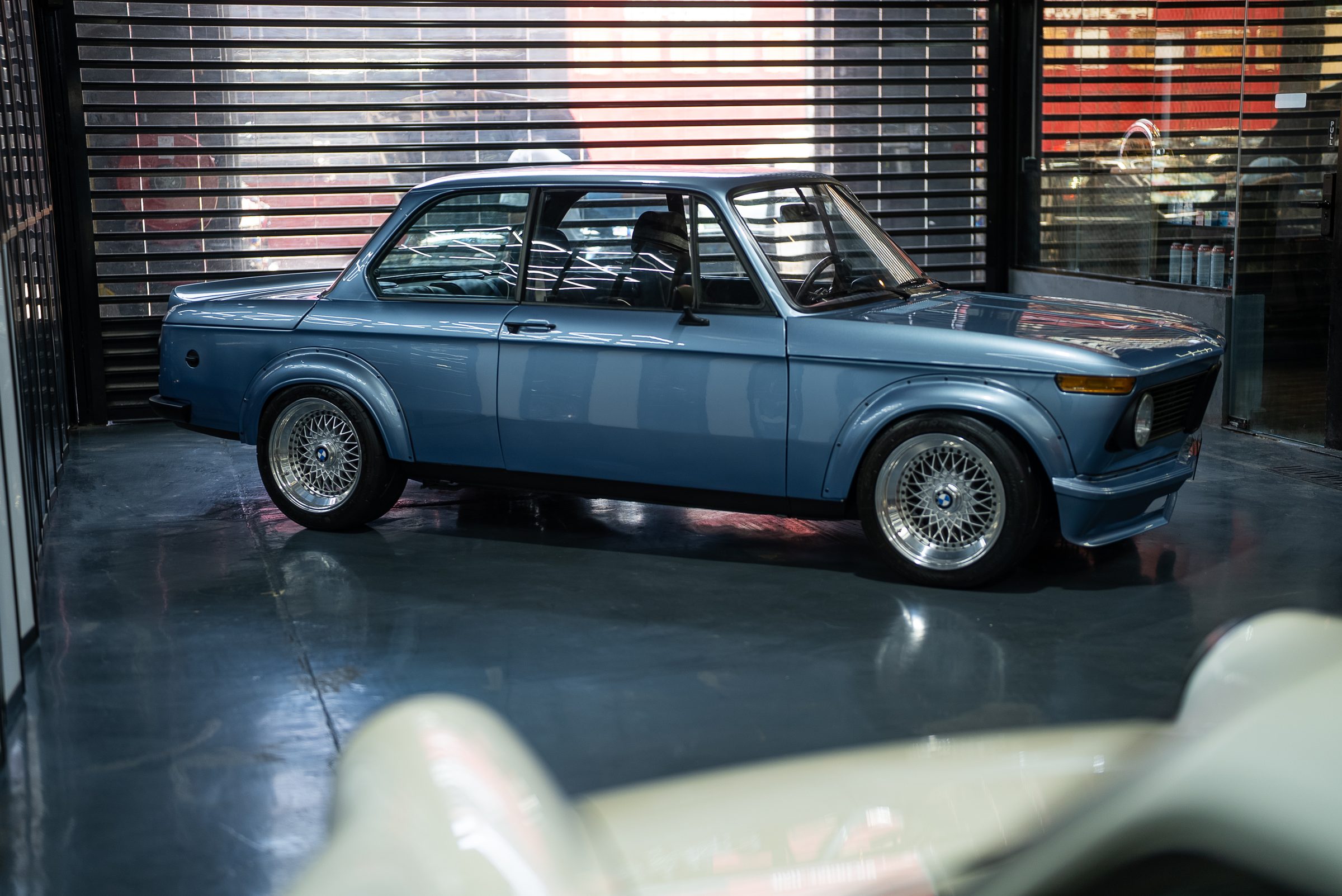 A blue BMW 2002 mid-restoration on the workshop floor