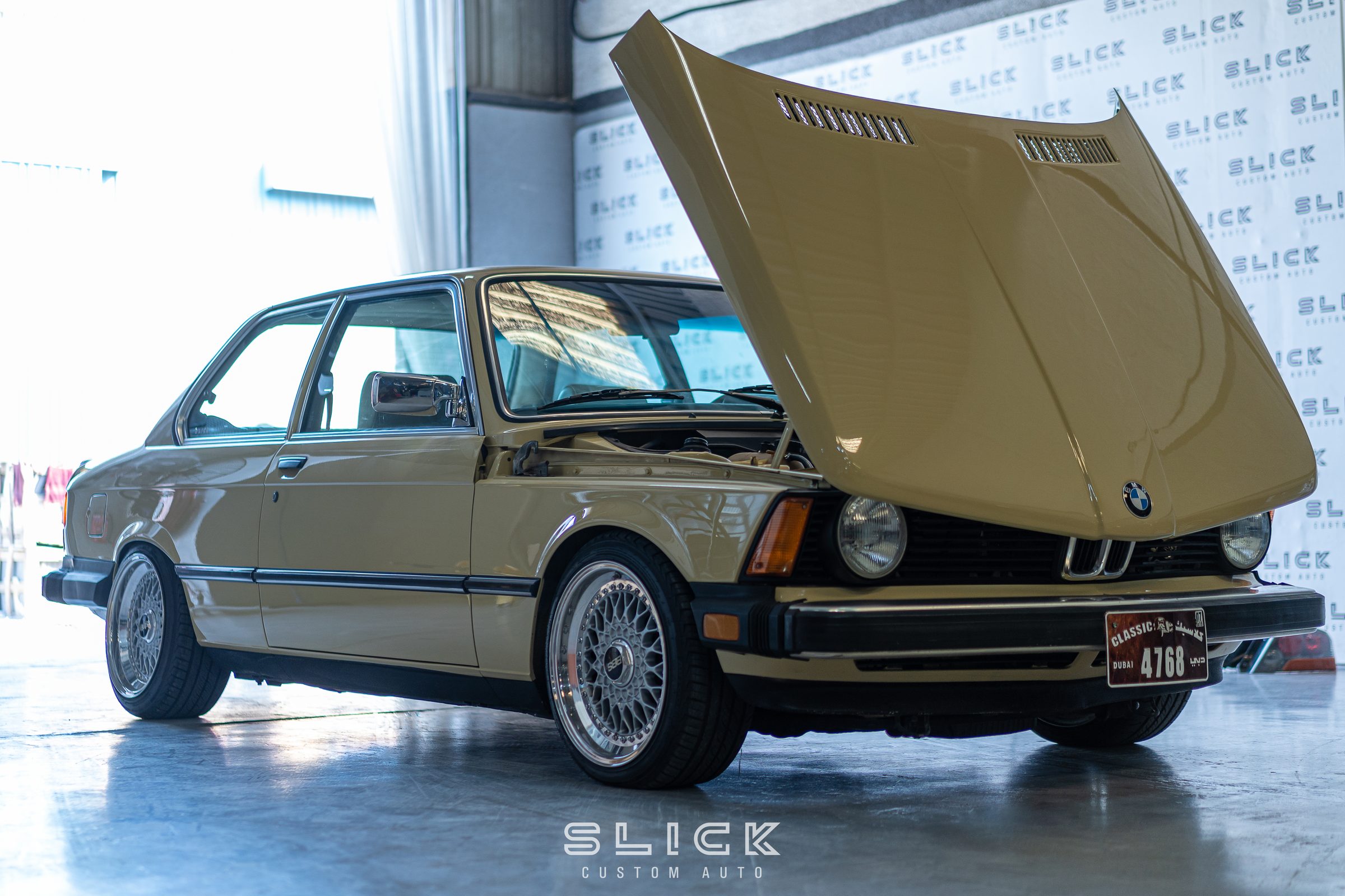 A classic BMW saloon with its bonnet raised during restoration