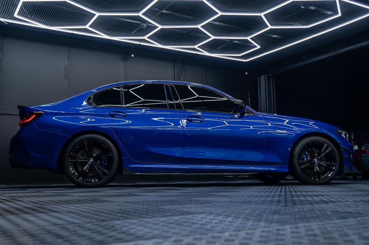 A blue BMW 3 Series under the studio lighting after detailing
