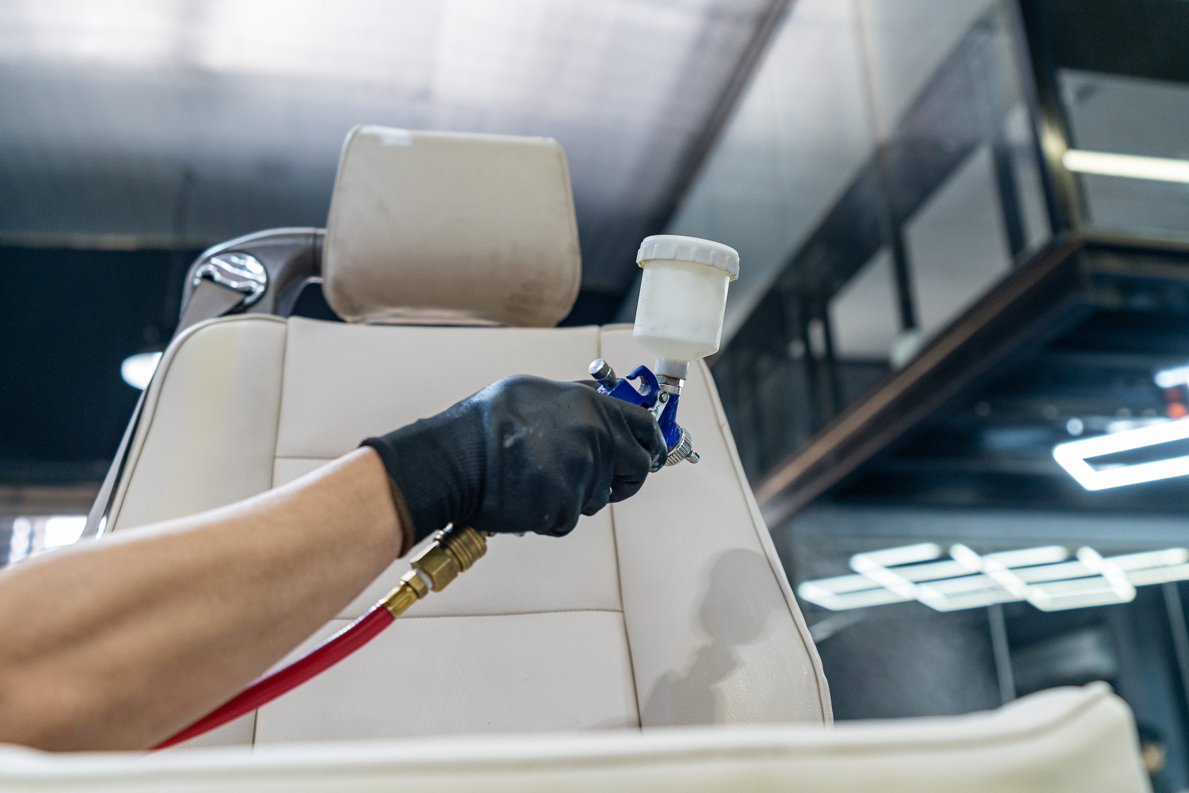 A detailer cleaning a cream leather seat by hand