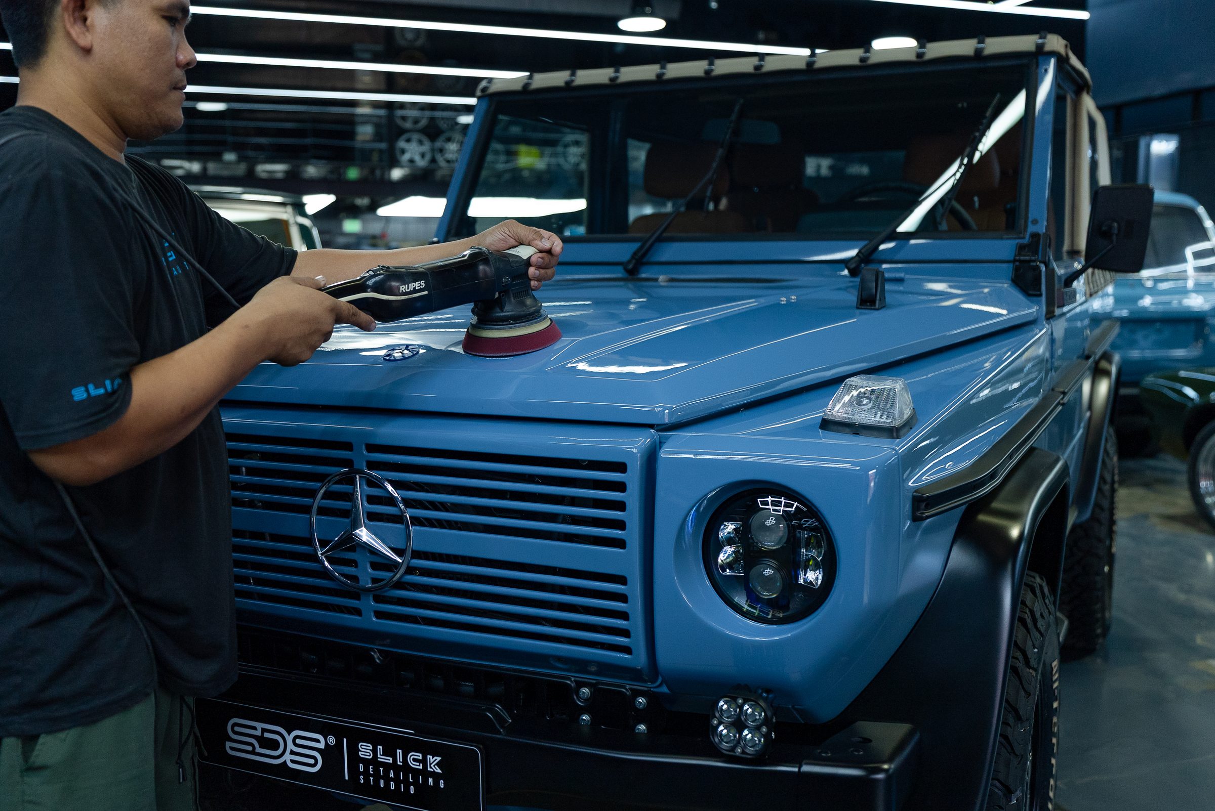 A blue Mercedes G-Class being machine polished in the studio