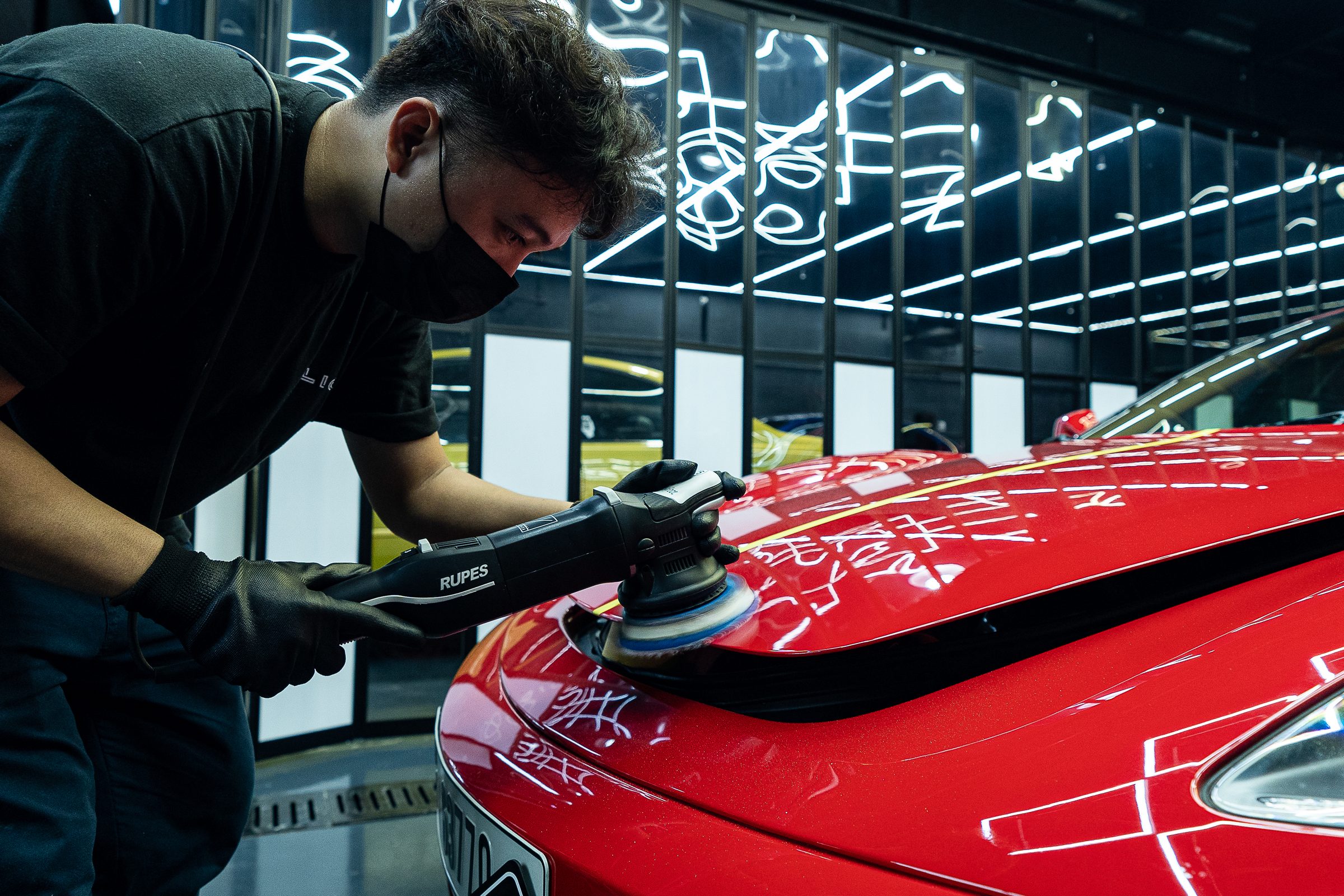 A red sports car being machine polished under the studio lighting