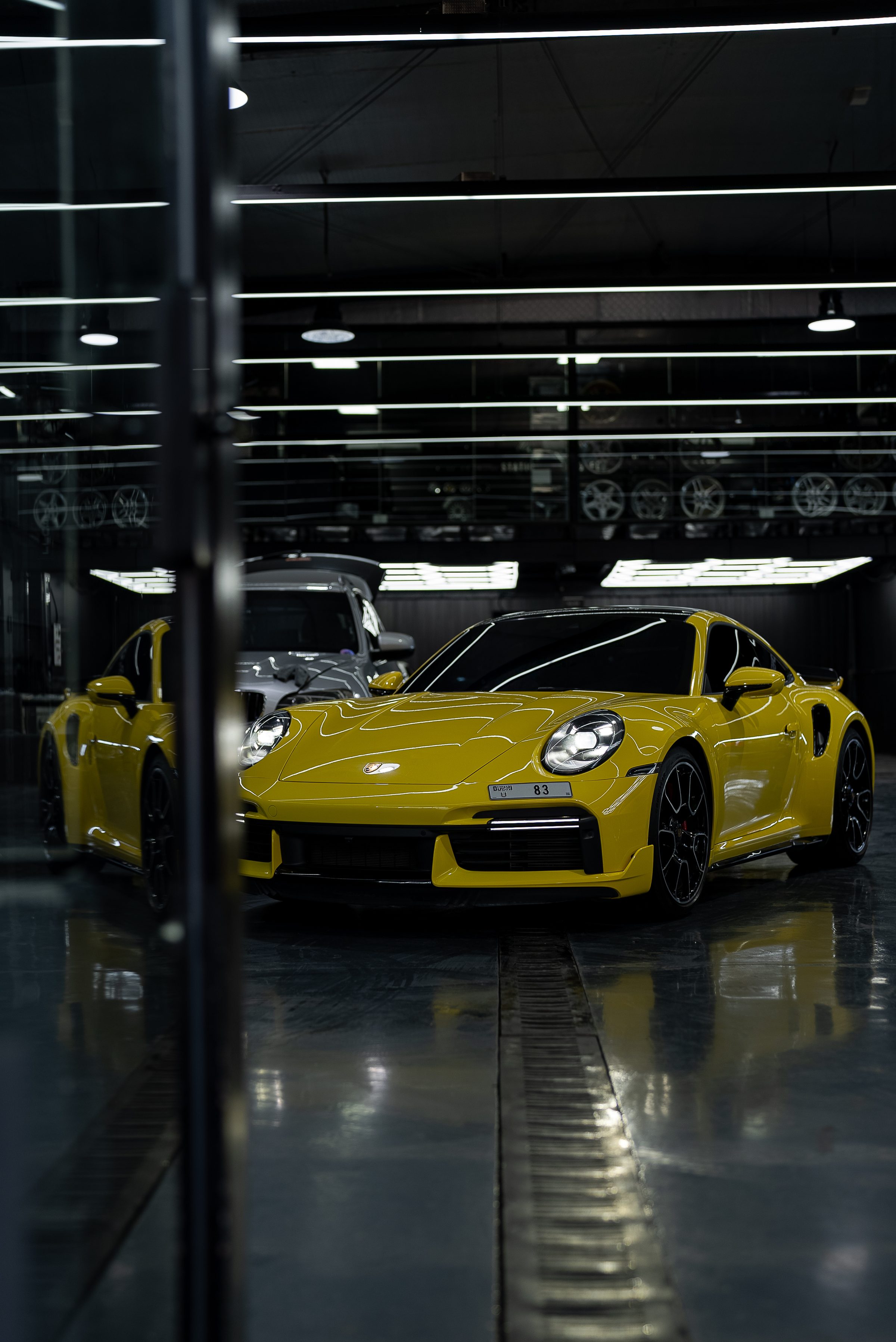 A yellow Porsche 911 in the dark detailing bay