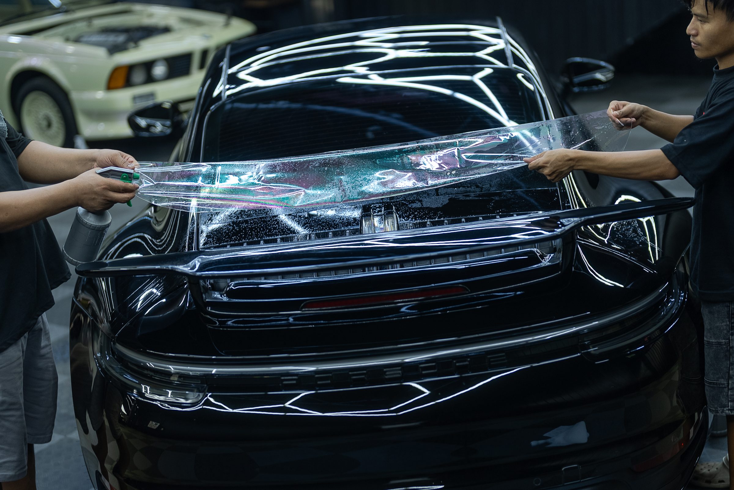 Protection film being laid over the front end of a black car