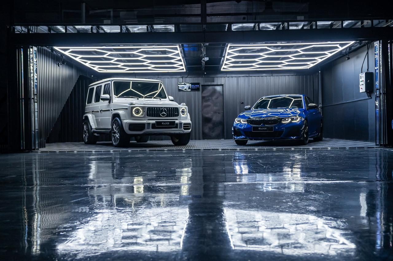 The Slick Detailing Studio bay with two cars under the hexagonal lighting