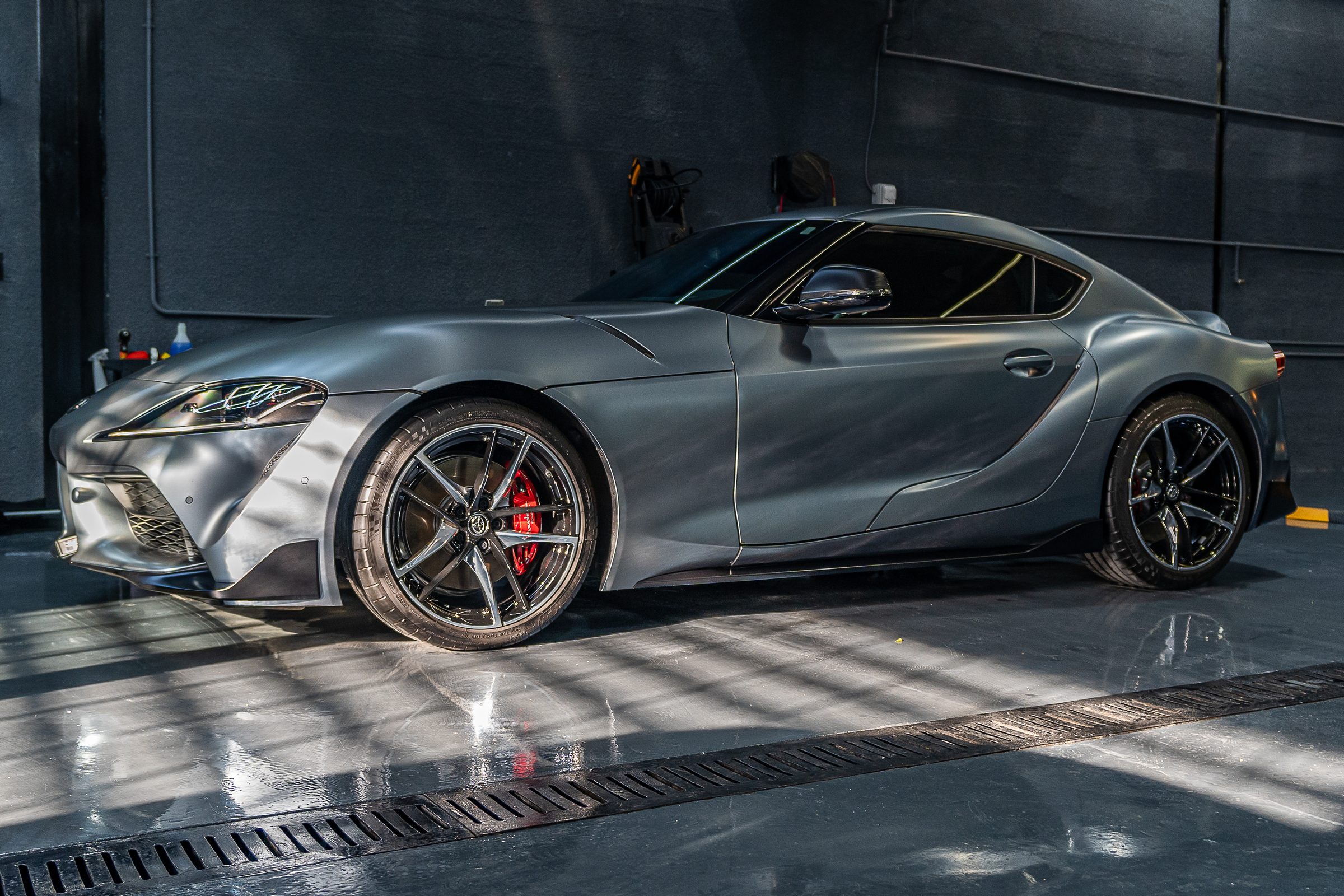 A grey Toyota Supra in profile inside the detailing studio