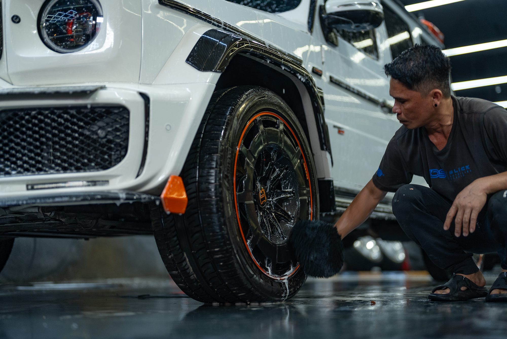 A detailer working on the wheels of a white G-Class