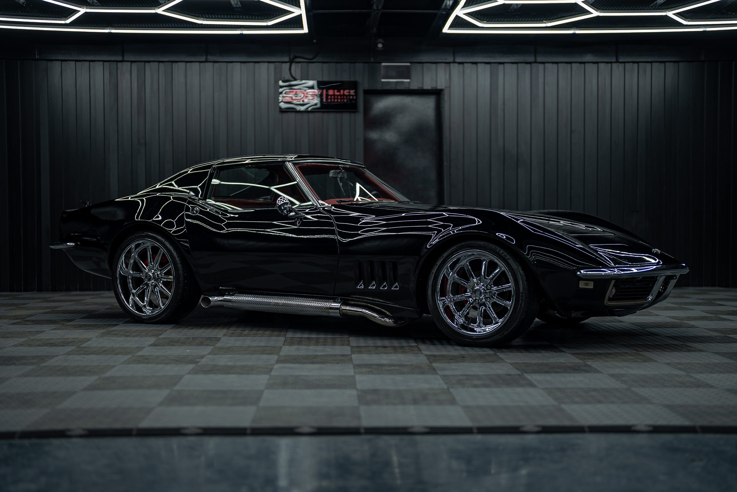A black classic Chevrolet Corvette in profile in a dark studio