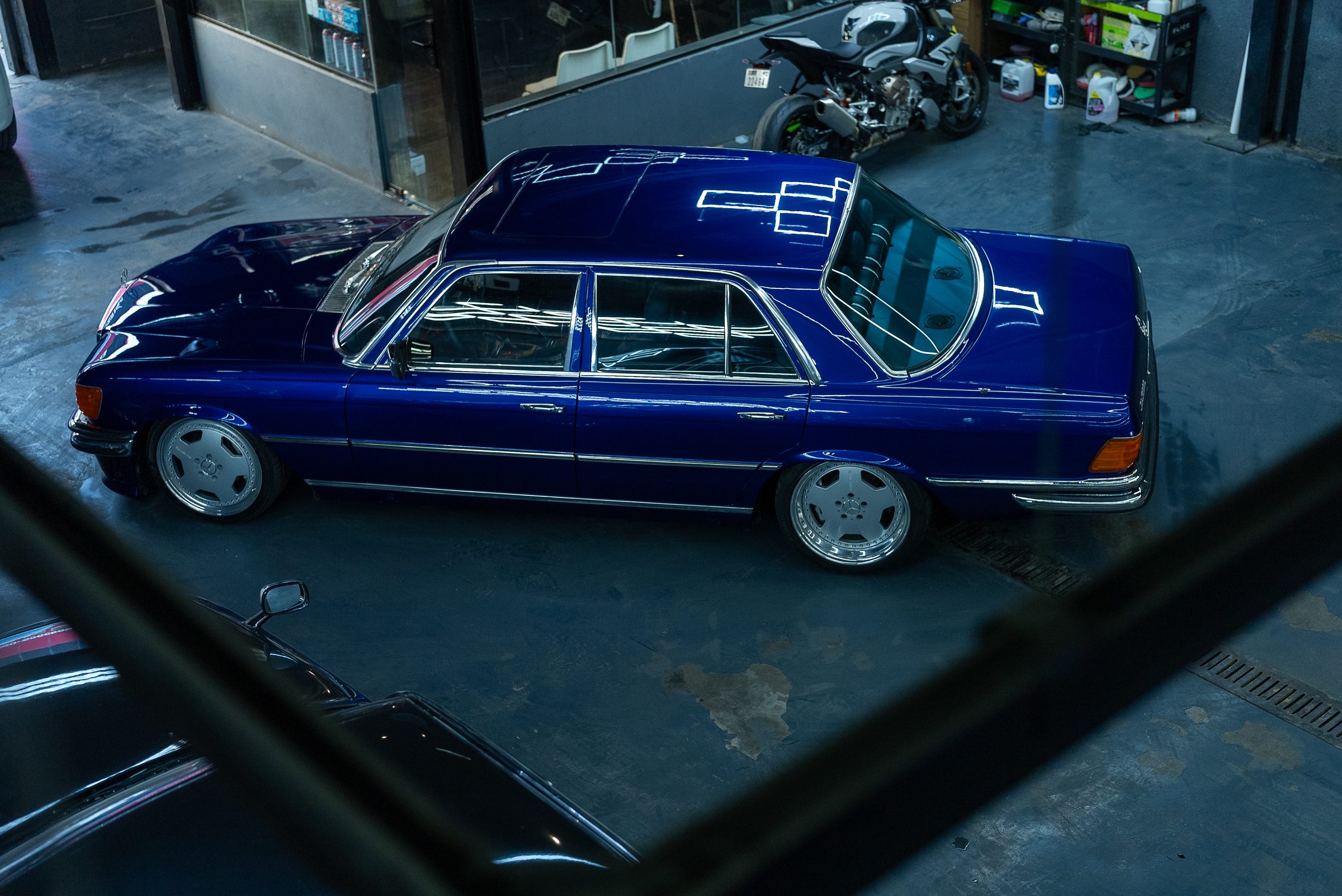 A blue classic Mercedes-Benz W126 saloon inside the workshop
