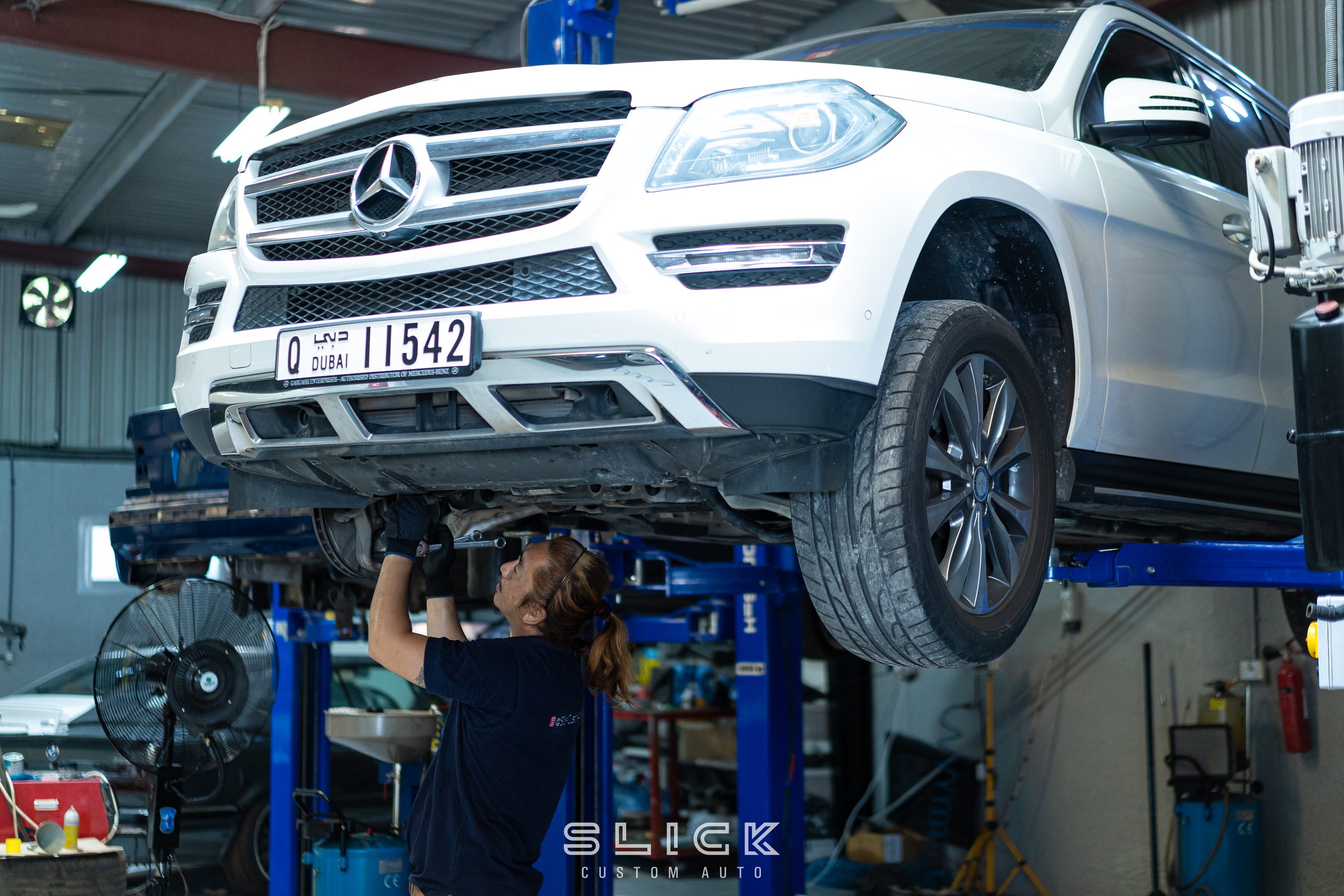 A technician working underneath a vehicle on a lift